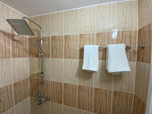 a shower with two white towels on a wall at Petra Sola Home in Wadi Musa