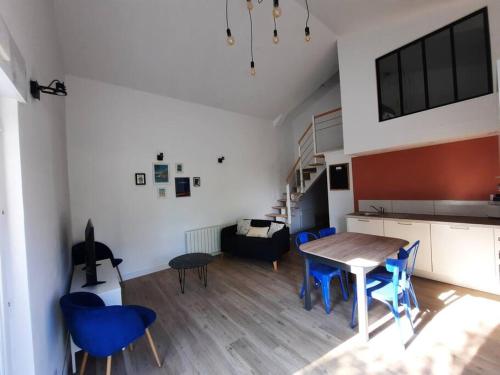 a living room with a table and blue chairs at L'inattendu in Saint-Alban