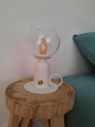 a glass lamp on a wooden table next to a bed at L'inattendu in Saint-Alban