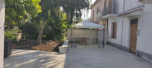 un patio con una mesa y una sombrilla blanca en Piccola LoLu en Ortona