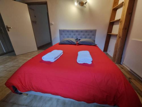 a red bed with two towels on top of it at Embrun Cosy in Embrun