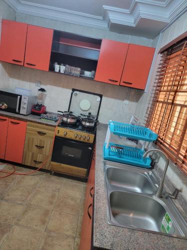 a kitchen with a sink and a stove and red cabinets at S&M HOUSE in Lekki