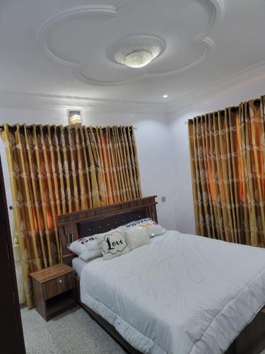 a bedroom with a bed and curtains and a ceiling at S&M HOUSE in Lekki