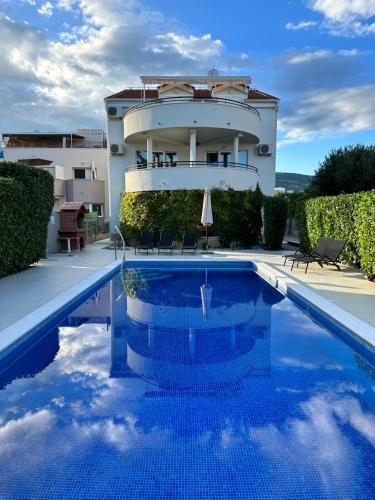 a house with a swimming pool in front of a building at Apartments Villa Ohana in Kaštela