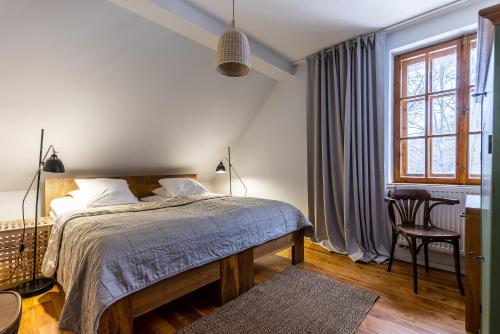 a bedroom with a bed and a chair and a window at Biały Dom W ROPKI in Ropki