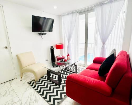 sala de estar con sofá rojo y TV en Departamento La Punta B - Piscina - Zona parrilla en Lima