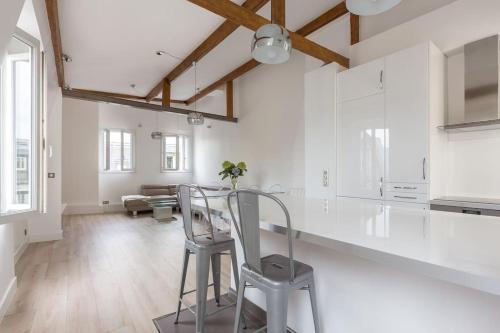 - une cuisine aux murs blancs avec une table et des chaises dans l'établissement Loft refait à neuf en dernier étage 2 chambres, à Paris