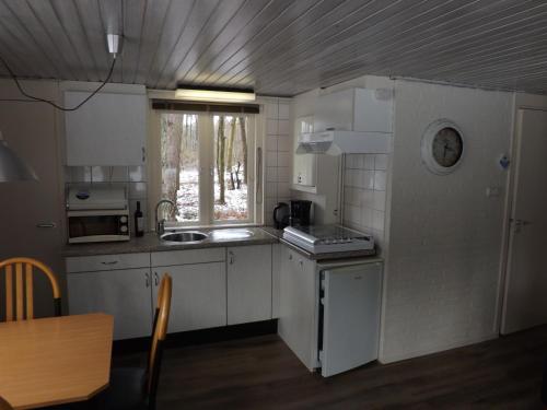 a small kitchen with white appliances and a window at Vosseven 27 Heksenkring in Stramproy