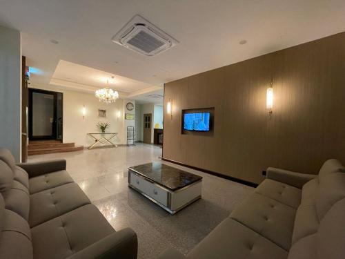 uma sala de estar com sofás e uma televisão na parede em Hotel Bundusan em Kota Kinabalu