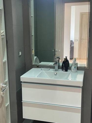 La salle de bains est pourvue d'un lavabo blanc et d'un miroir. dans l'établissement Nice appartement pool & sea view, à Dar Bouazza
