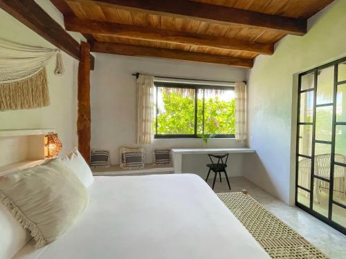 a bedroom with a large white bed and a window at Amansala Resort in Tulum