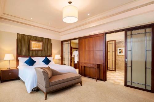 The Hongta Hotel, A Luxury Collection Hotel, Shanghai في شانغهاي: غرفة نوم بسرير وكرسي في غرفة
