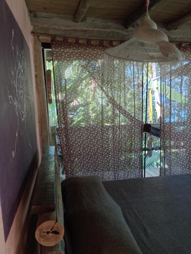 a bedroom with a bed and a window with a curtain at Canto de Paz Trindade Hospedagem in Trindade