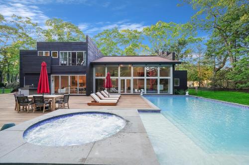 a house with a swimming pool in front of a house at Enjoy the Spa all year round in this EHV Estate in East Hampton