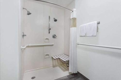 a white bathroom with a shower and a tub at Clarion Pointe - Greensboro Coliseum Area in Greensboro