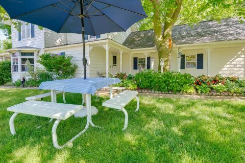 a table and benches with an umbrella in front of a house at Elegant 1905 Home Steps to Torch Lake and Dtwn in Alden