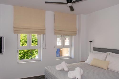 a bedroom with two white towels on a bed with two windows at Gioia I & Gioia II in Rethymno