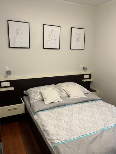 a bed in a bedroom with three pictures on the wall at Apartament Esensja II in Szklarska Poręba