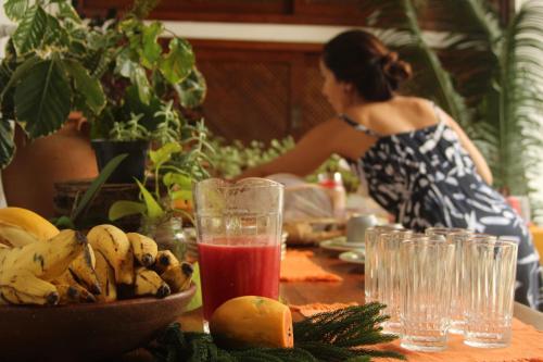 kobieta siedząca przy stole z miską owoców w obiekcie Pousada Emcontrei w mieście São João da Barra