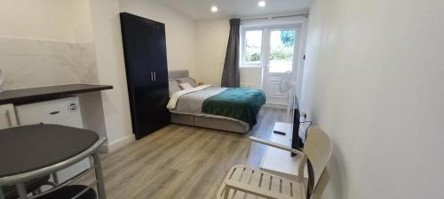 ein kleines Zimmer mit einem Bett, einem Tisch und einem Fenster in der Unterkunft Stylish Home from Home in Orpington