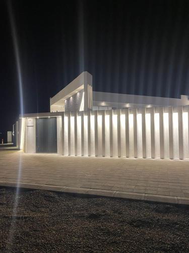 a white fence in front of a building at night at JHR chalet in Salalah