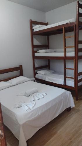 a room with two bunk beds with white sheets at Hospedaje MorroSP in Morro de São Paulo