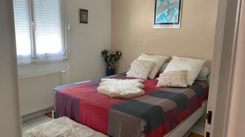 ein Schlafzimmer mit einem Bett mit einer bunten Decke und Kissen in der Unterkunft Maison quiétude in Chavanoz