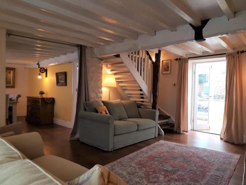 a living room with a couch and a staircase at Cruck Cottage in Pickering