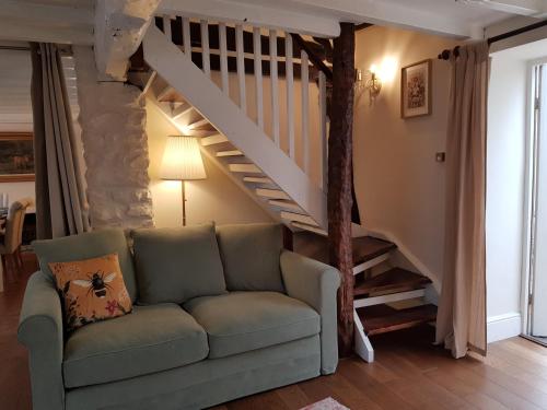 a living room with a couch and a staircase at Cruck Cottage - Gorgeous 300 Year Old Cottage Mins from North Yorkshire Moors, Steam Trains and Picturesque Pickering in Pickering