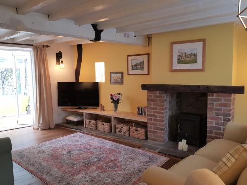 a living room with a fireplace and a tv at Cruck Cottage in Pickering