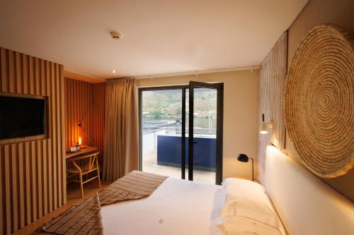 a hotel room with a bed and a sliding glass door at Hotel Folgosa Douro in Armamar