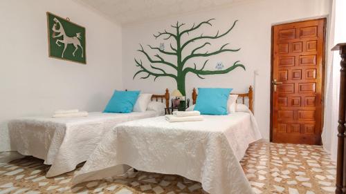 2 camas en una habitación con un árbol en la pared en Casa rural mirador de sole, en Cazorla