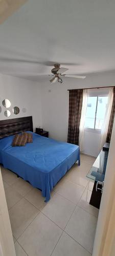 a bedroom with a blue bed and a window at Departamento Temporario - Barrio San Isidro (Malibu) in Villa Allende