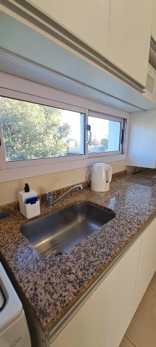 encimera de cocina con fregadero y 2 ventanas en Departamento Temporario - Barrio San Isidro (Malibu) en Villa Allende