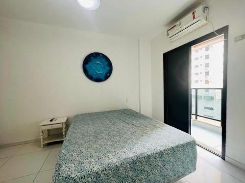 - une chambre avec un lit et une horloge murale dans l'établissement 6 Flats Capitania Varan, Pitangueiras, wifi, à Guarujá