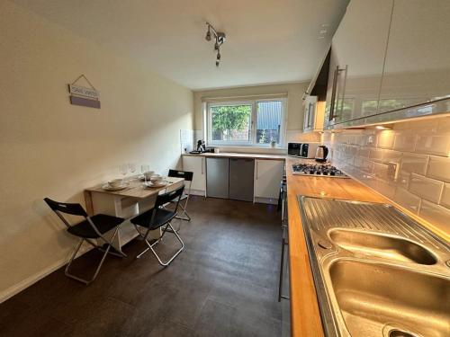 a kitchen with a sink and a table with chairs at The Red Door, Two-Bedrooms Apartment in Edinburgh