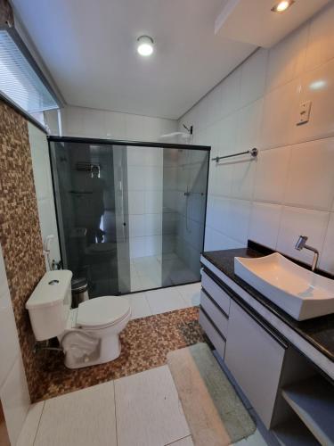 a bathroom with a toilet and a shower and a sink at Residência Wimbledon in Ilhéus