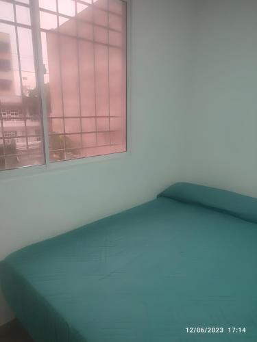 an empty room with two windows and a green mattress at Habitación en casa ambiente familiar in Cartagena de Indias