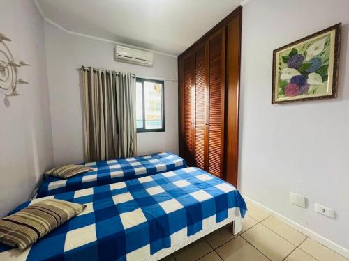 - un lit bleu et blanc dans une chambre avec fenêtre dans l'établissement 1 Flats Capitania Varan, Wifi, Pitangueiras vista ao mar, à Guarujá