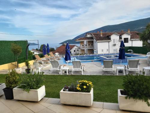 a pool with chairs and umbrellas in a yard at Apartmani Niksic in Herceg-Novi