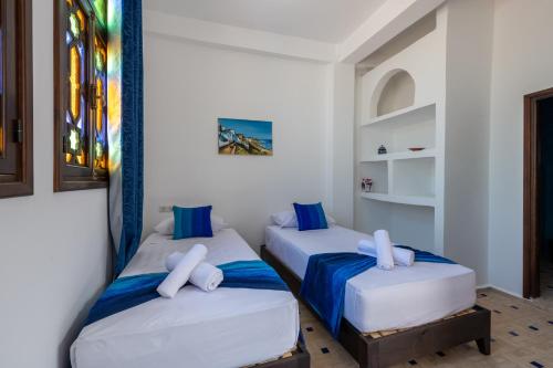 two beds in a room with blue and white at Riad SULTANA in Tangier