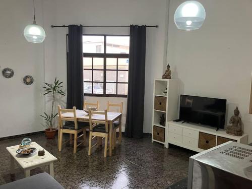 a living room with a dining room table and a television at Apartamento en Gran Tarajal in Gran Tarajal