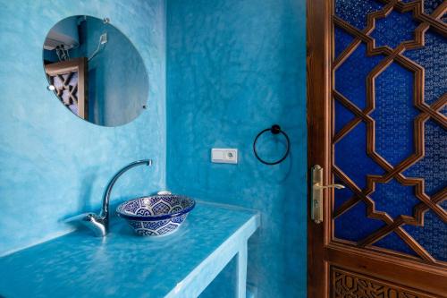 a blue bathroom with a sink and a mirror at Riad SULTANA in Tangier