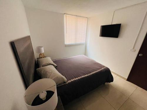 een kleine slaapkamer met een bed en een televisie bij Hermoso departamento a dos cuadras de Col. Roma in Mexico-Stad