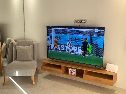een flatscreen-tv op een houten standaard naast een stoel bij Luxury Apartment 105sqm Terrace Seafront WIFI Unlimited in Agadir