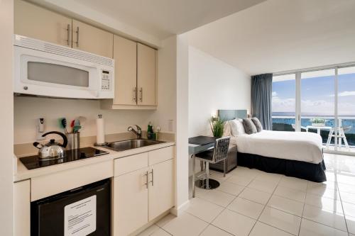 a bedroom with a bed and a kitchen with a sink at Ocean View Balcony steps from Restaurants, Peacock Park & Marina in Miami