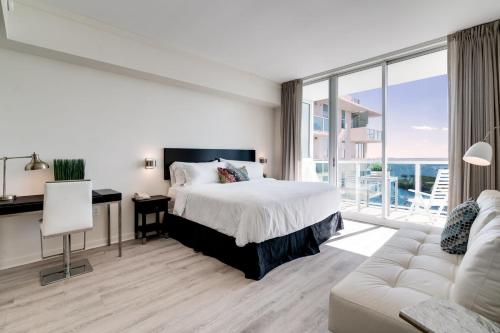 a bedroom with a bed and a desk and a couch at Ocean View Balcony steps from Restaurants, Peacock Park & Marina in Miami