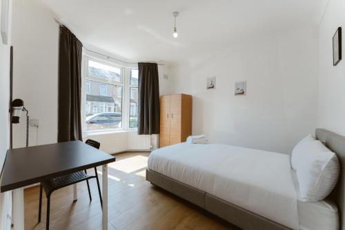 Schlafzimmer mit einem Bett, einem Schreibtisch und einem Fenster in der Unterkunft Plaistow Cosy Double Rooms - 8 in London