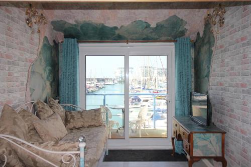 a living room with a couch and a large window at Unique, loft-style apartment with fantastic Brighton Marina views in Brighton & Hove