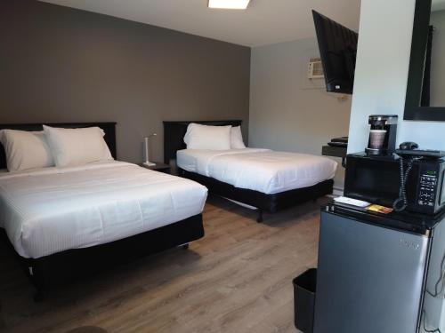 a hotel room with two beds and a television at Traveler's Inn in Kenora